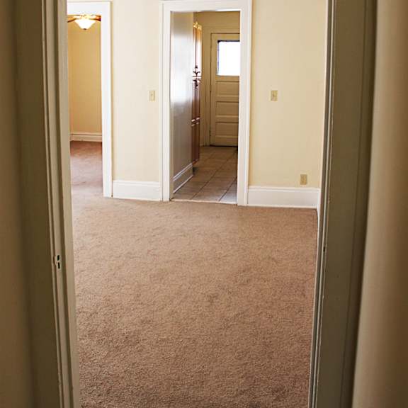 a hallway with a carpeted floor and a doorway leading to another room.