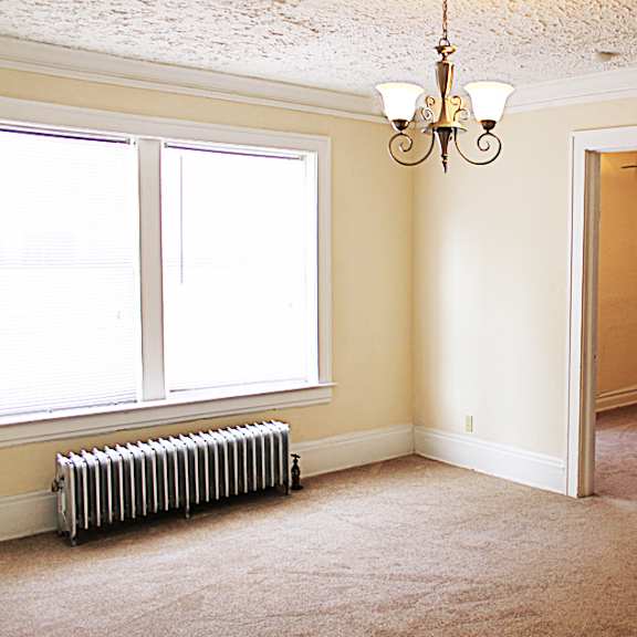 a room with a chandelier, a window, and a radiator.