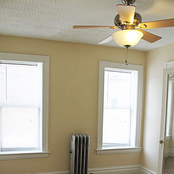 a room with a carpeted floor, a ceiling fan, and a window with blinds.