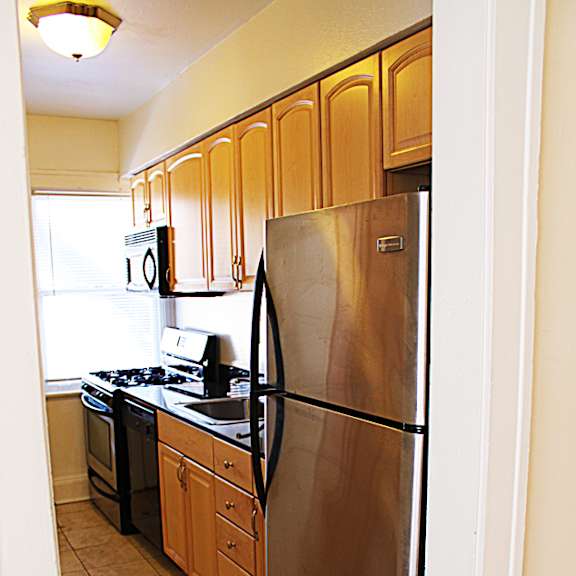 a kitchen with a stainless steel refrigerator and wooden cabinets.