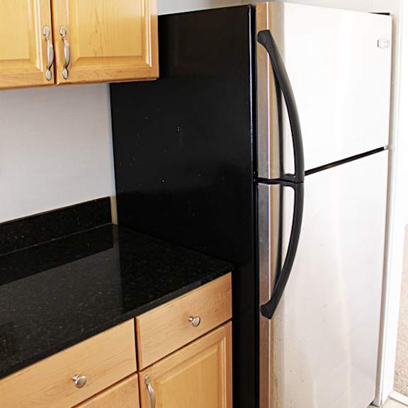 a black refrigerator with a black handle sits next to a white refrigerator.