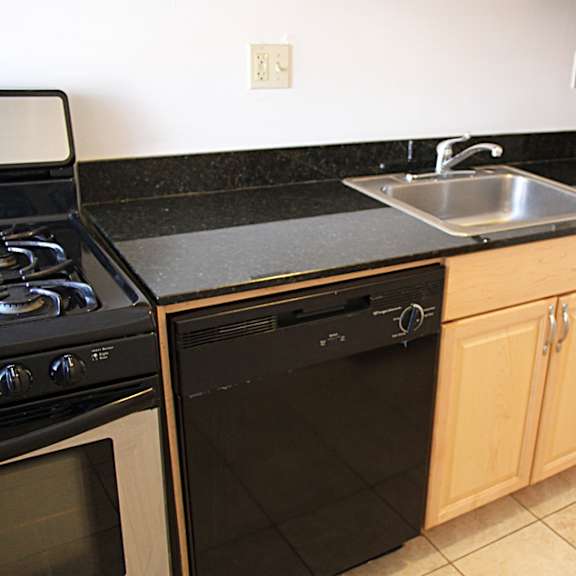 a black stove top oven and black oven with a silver sink and wooden cabinets.