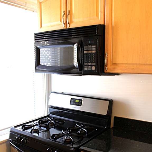 a black stove top oven with four burners and a microwave above it.