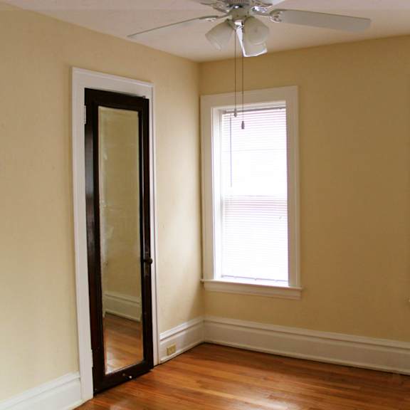 a room with a ceiling fan and two windows.