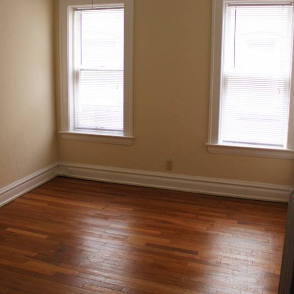 a room with a ceiling fan and two windows.