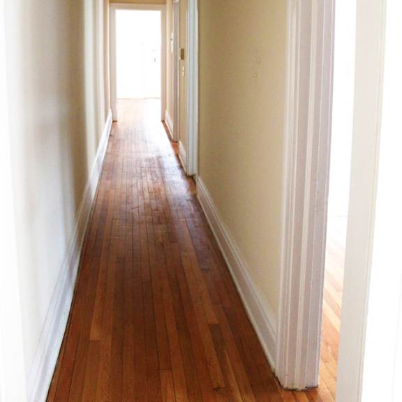 a long hallway with wood floors and white walls.