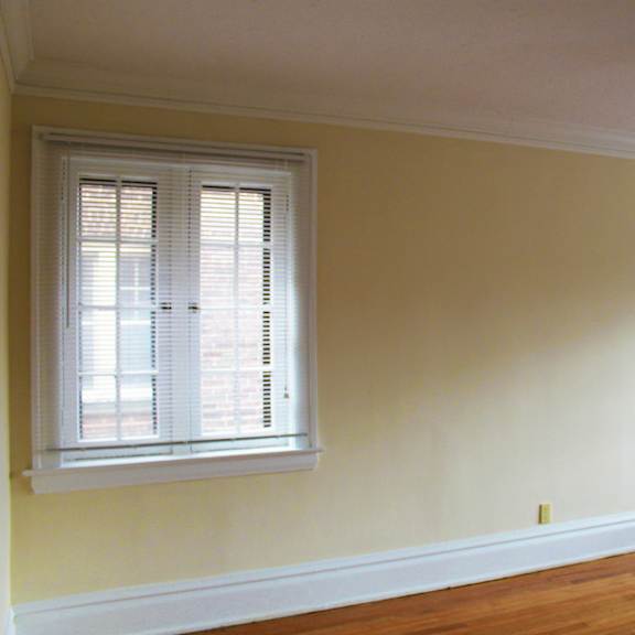 a room with a ceiling fan and two windows.
