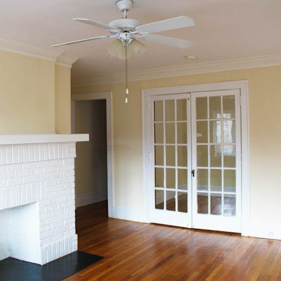 a white fireplace with a black hearth sits in a room with a ceiling fan.