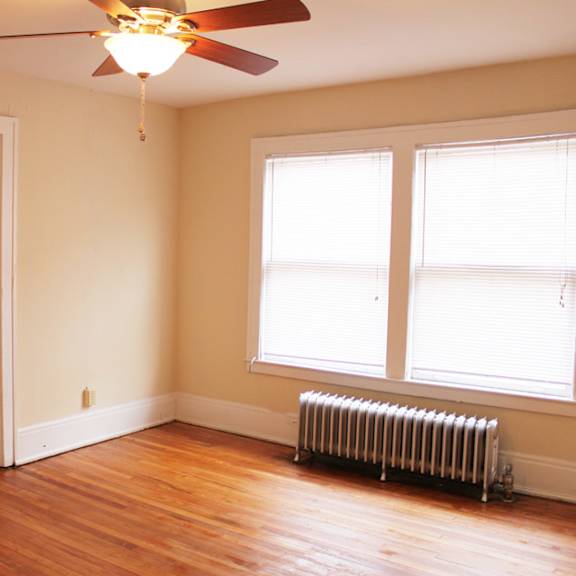 a room with a ceiling fan and a radiator beneath a window.