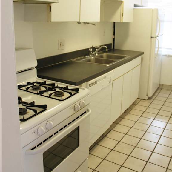 a kitchen with a stove, sink, and refrigerator.