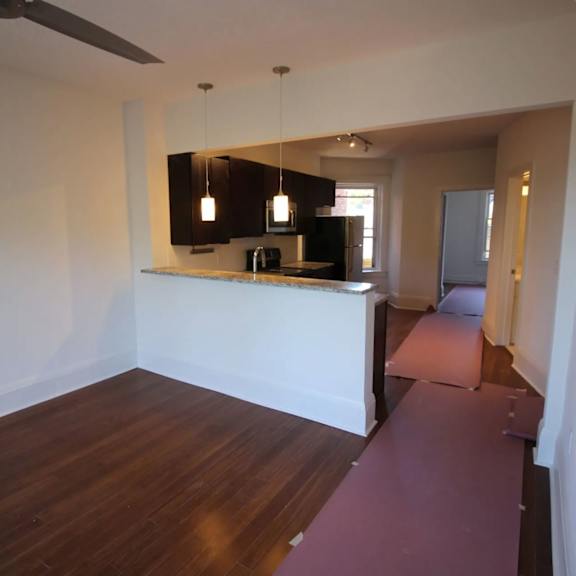 a room with a kitchen area and a long purple rug.