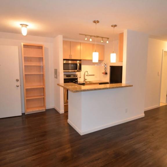 a kitchen with a white counter and wooden floors.