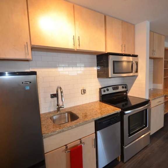 a kitchen with a refrigerator, microwave, oven, and sink.