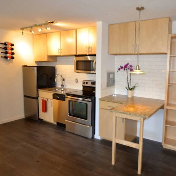 a kitchen with a refrigerator, oven, microwave, and a table with a vase of flowers on it.