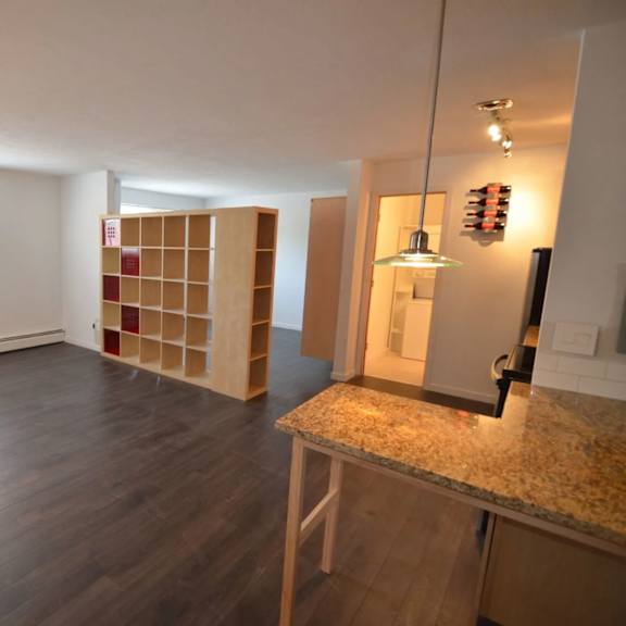 a room with a wooden floor and a kitchen island with a granite countertop.