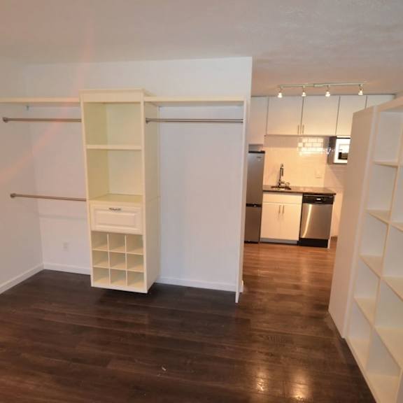 a white cabinet with a drawer is in a room with wood floors.