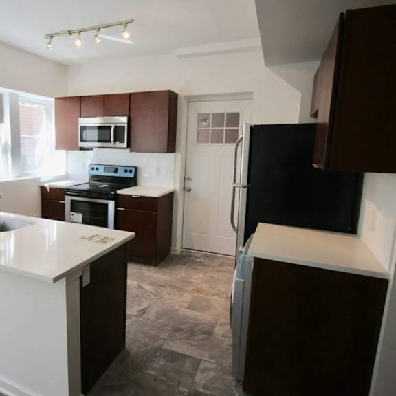a kitchen with a white counter top and brown cabinets.