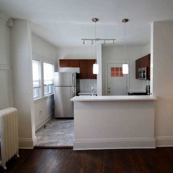 a kitchen with white walls and wooden floors.