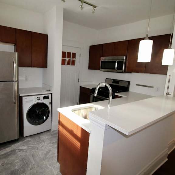 a kitchen with white countertops and a stainless steel refrigerator.