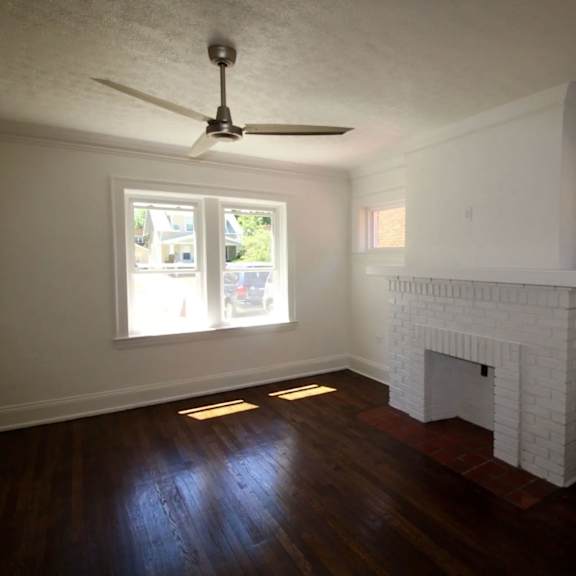 a room with a fireplace and a ceiling fan.