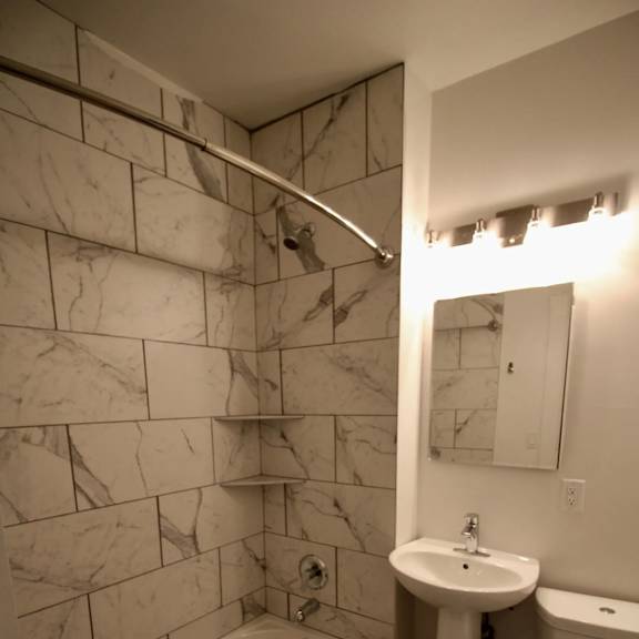 a bathroom with a marble tile wall and a white toilet.
