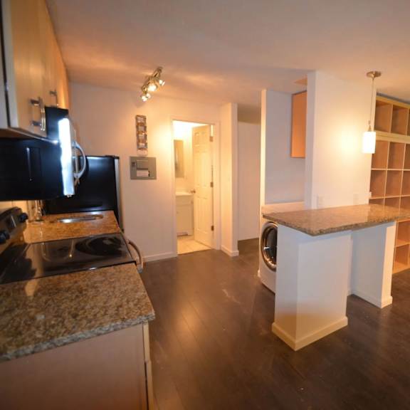 a kitchen with granite countertops and a washer and dryer in the background.