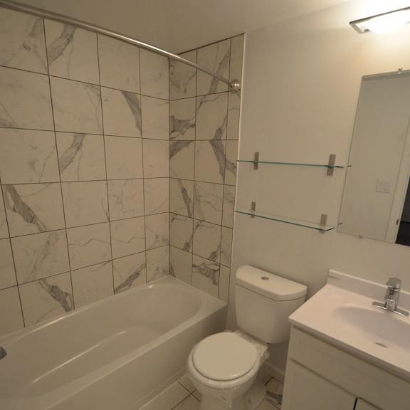 a white toilet sits next to a bathtub in a bathroom.