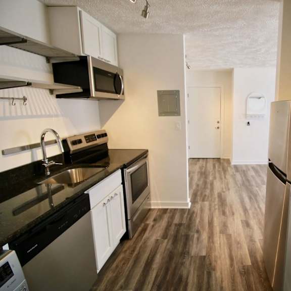 a kitchen with black countertops and stainless steel appliances.