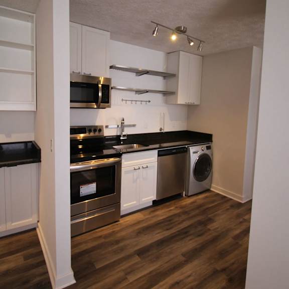 a kitchen with white cabinets and black countertops.
