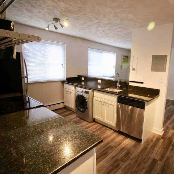 a kitchen with a black counter top and stainless steel appliances.