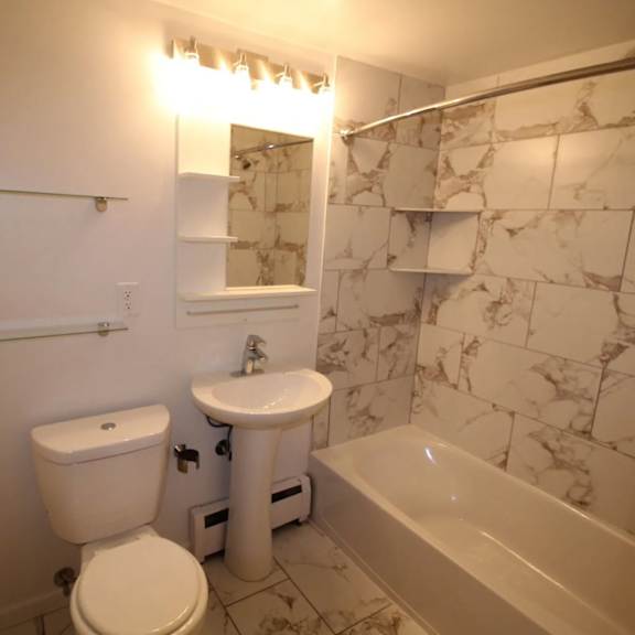 a white toilet and sink in a bathroom with marble tiles.