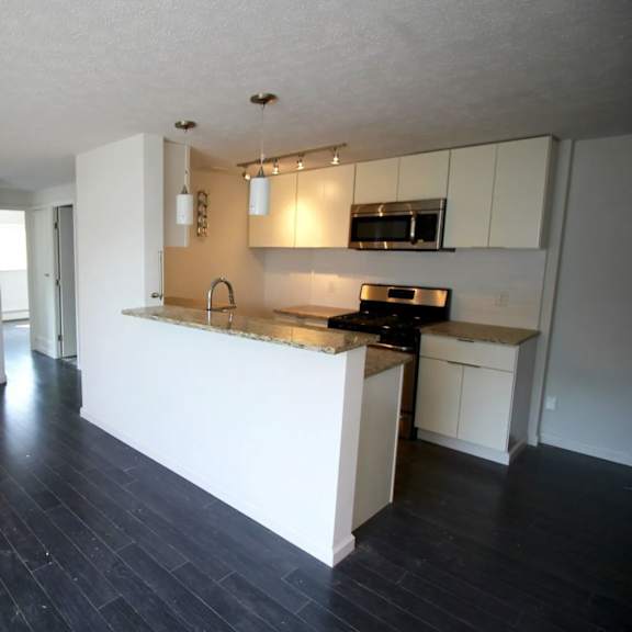 a kitchen with white cabinets and black countertops.