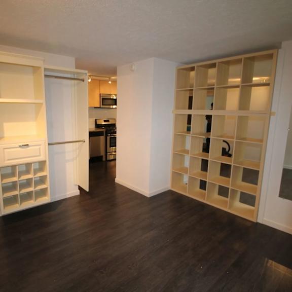 a kitchen with a white fridge and a white cabinet with shelves.