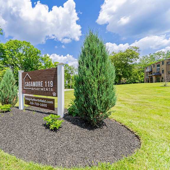 a sign for sagamore farms is displayed in a landscaped area.