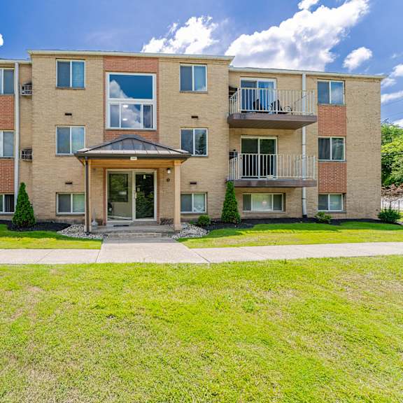 a large apartment building with a grassy front yard.