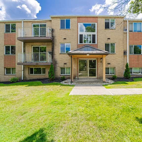 a large apartment building with a grassy front yard.