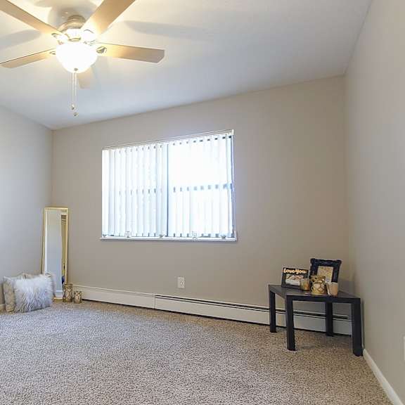 carpeted apartment bedroom option with ceiling fan light.