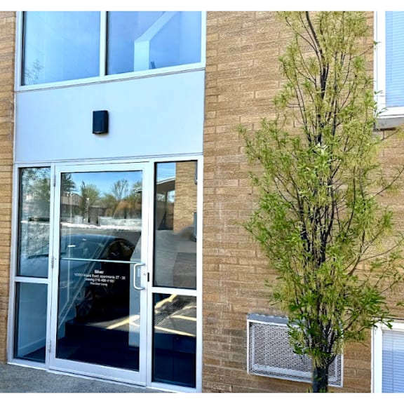 a building with a glass door and two trees on either side.