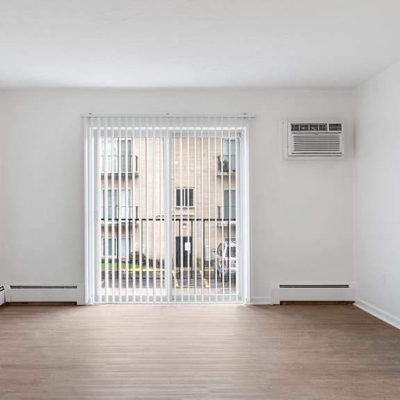 a room with a white wall and a window with a view of a building outside.