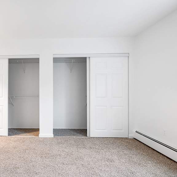 a bedroom with a carpeted floor and dual closets.