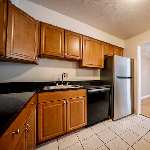 a kitchen with wooden cabinets and a black counter top at westwood meadows, westlake, oh, 44145