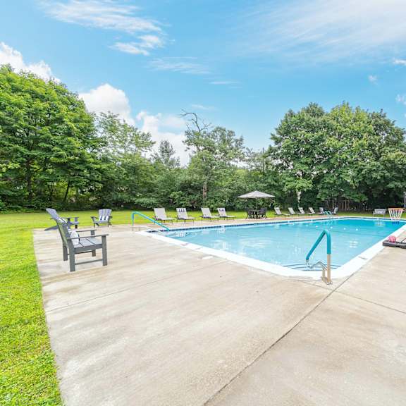 a swimming pool surrounded by trees and lawn chairs.