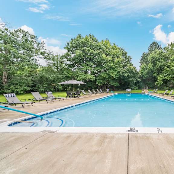 a large outdoor swimming pool surrounded by trees and lounge chairs.