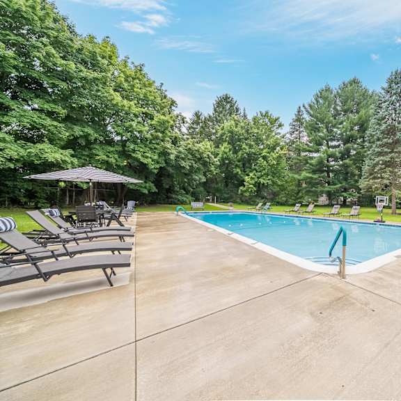 a large outdoor swimming pool surrounded by trees and lounge chairs.