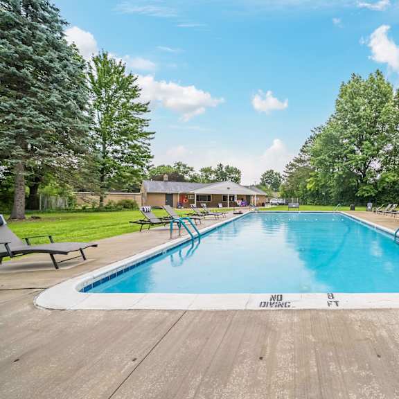 a large outdoor swimming pool surrounded by trees and lounge chairs.