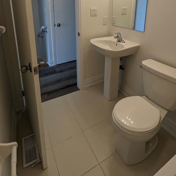 a bathroom with a toilet, sink, and mirror.