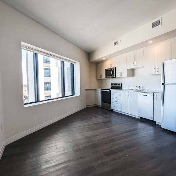 a kitchen with a refrigerator, cabinets, and a window.