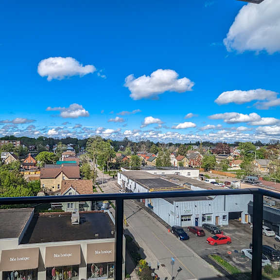 a view from a high vantage point looking down at a town with buildings, cars, and a clear blue sky with clouds.