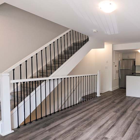 a spacious room with a staircase and a kitchen area.