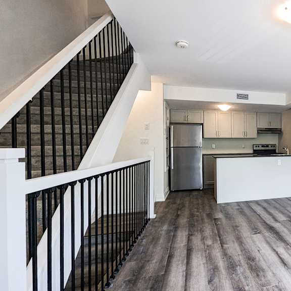 a spacious room with a staircase and a kitchen area.